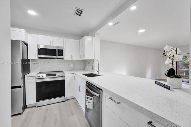 856 NW 47th St Unit 856, Deerfield Beach, FL 33064 - kitchen featuring stainless steel appliances, light wood-style floors, light stone countertops, white cabinets, and decorative backsplash
