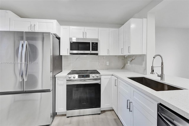 856 NW 47th St Unit 856, Deerfield Beach, FL 33064 - kitchen featuring light stone counters, a sink, light wood finished floors, stainless steel appliances, and white cabinetry