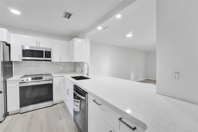 856 NW 47th St Unit 856, Deerfield Beach, FL 33064 - kitchen with decorative backsplash, recessed lighting, white cabinets, a sink, and stainless steel appliances