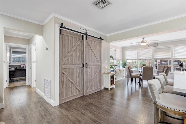interior space featuring ceiling fan, visible vents, a barn door, and dark wood finished floors