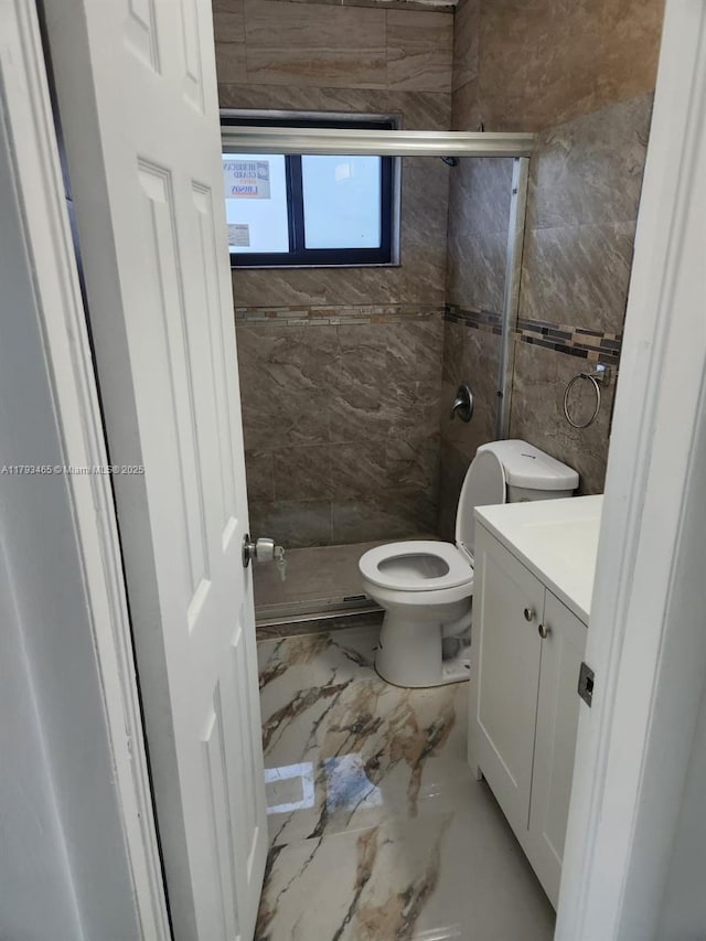 bathroom with vanity, marble finish floor, toilet, tile walls, and a stall shower