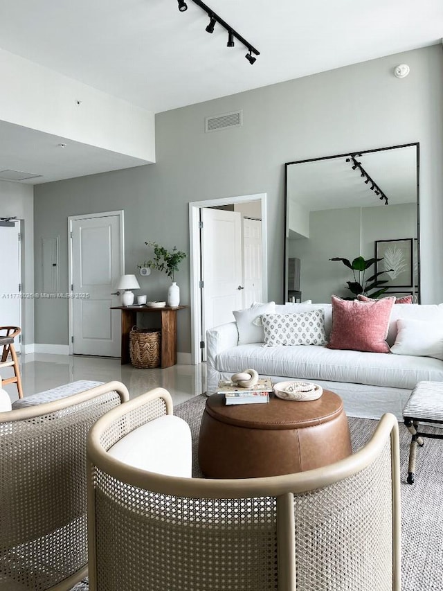 living room with rail lighting, visible vents, and baseboards