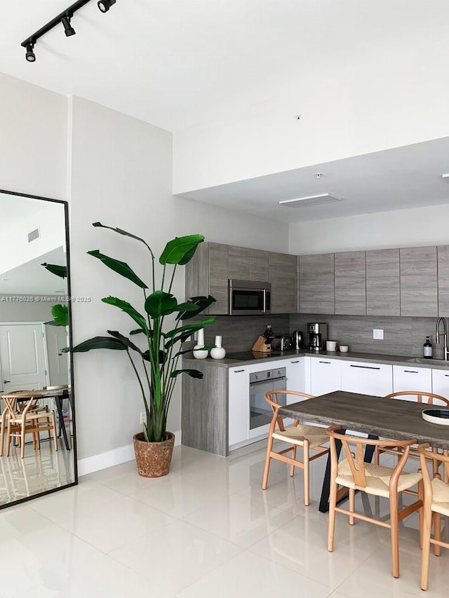 kitchen with decorative backsplash, wall oven, modern cabinets, stainless steel microwave, and gray cabinetry