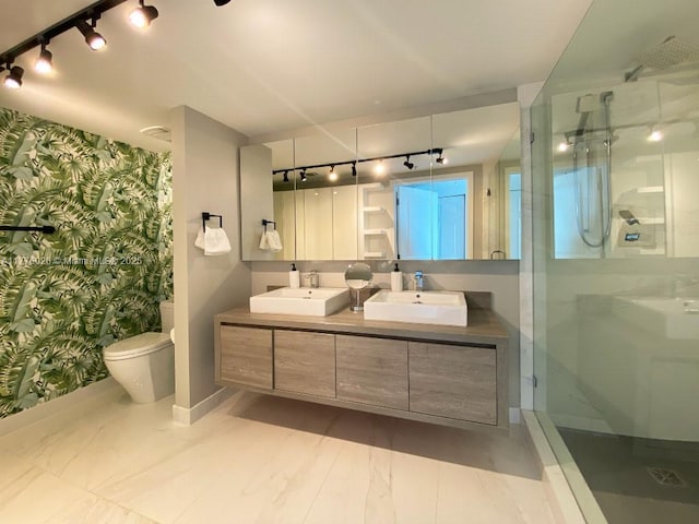 bathroom featuring track lighting, a sink, a shower stall, and wallpapered walls