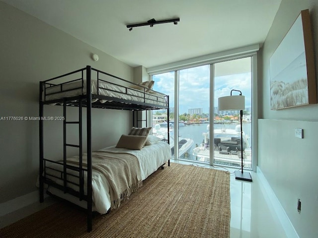 bedroom with access to outside, floor to ceiling windows, and a water view
