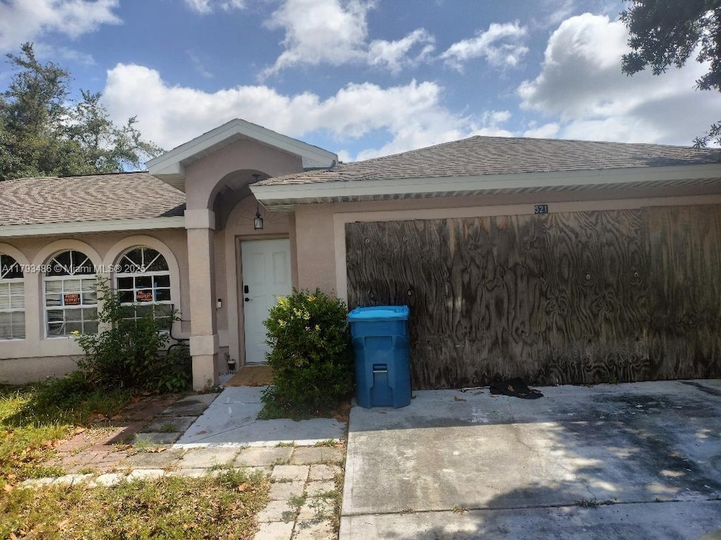 property entrance featuring roof with shingles and stucco siding