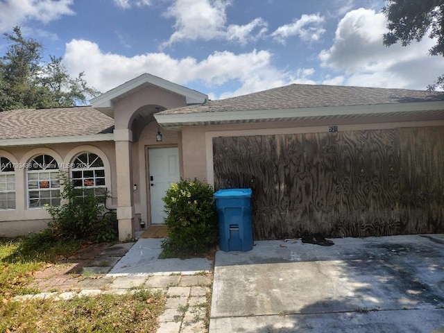 property entrance featuring roof with shingles and stucco siding