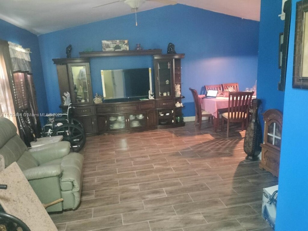 living room with a ceiling fan and lofted ceiling