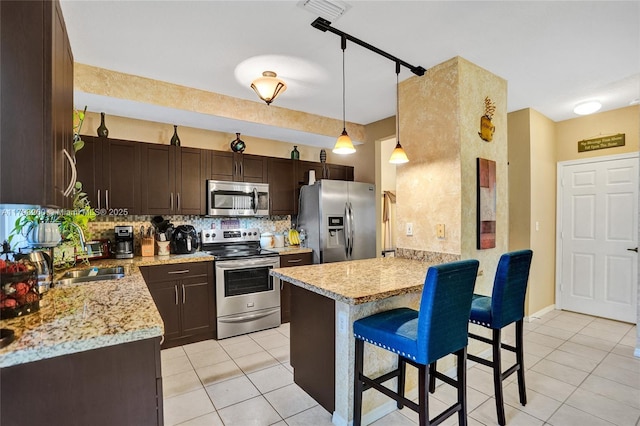 kitchen with dark brown cabinetry, a sink, a peninsula, stainless steel appliances, and light tile patterned flooring
