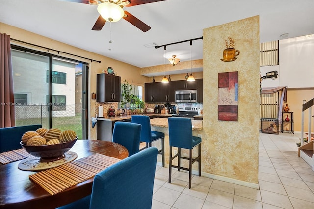 dining room featuring track lighting, baseboards, ceiling fan, and light tile patterned floors