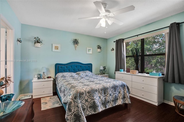 bedroom with dark wood-type flooring, a ceiling fan, and baseboards