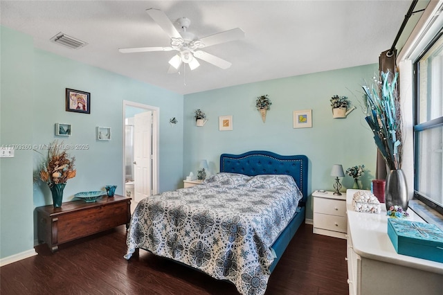bedroom with visible vents, wood finished floors, baseboards, ceiling fan, and ensuite bath