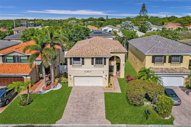 mediterranean / spanish house featuring a residential view, an attached garage, stucco siding, and decorative driveway