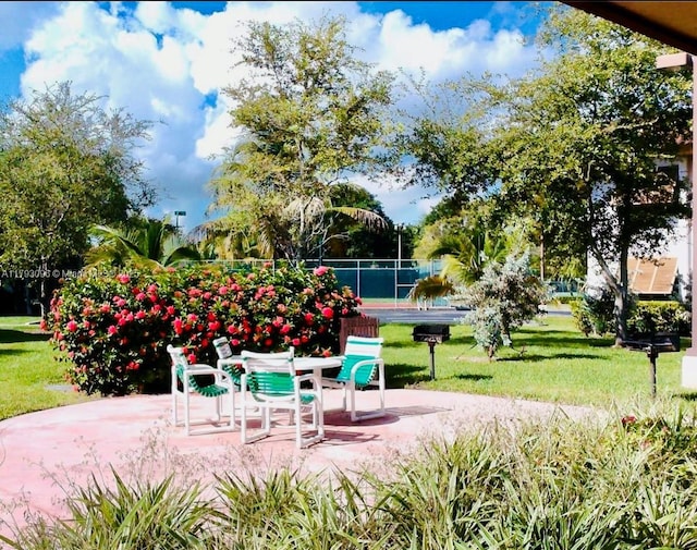 view of community with a lawn, a patio, and fence