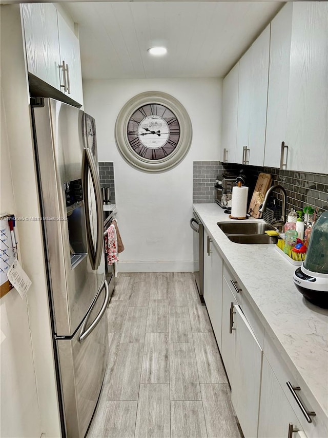 kitchen featuring a sink, appliances with stainless steel finishes, tasteful backsplash, and light wood finished floors