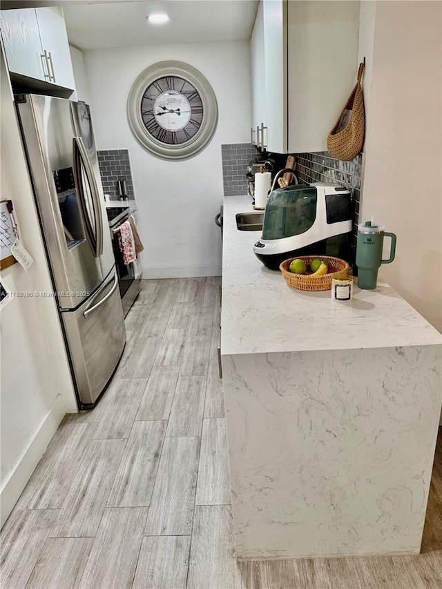 kitchen featuring light wood-type flooring, light countertops, appliances with stainless steel finishes, and tasteful backsplash