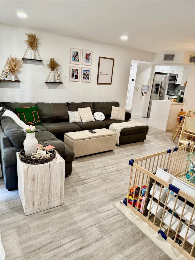 living room featuring light wood finished floors, recessed lighting, and visible vents