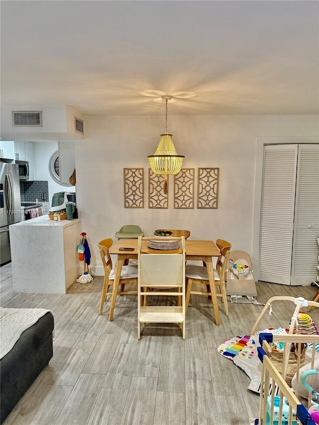 dining room with baseboards, visible vents, and light wood-style floors