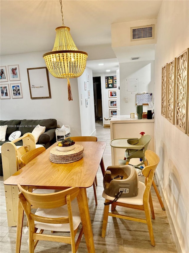 dining room with an inviting chandelier, light wood-type flooring, and visible vents