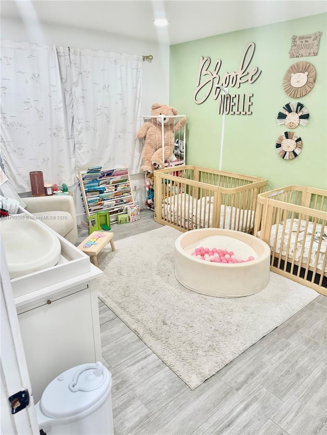 bedroom with a nursery area and wood finished floors