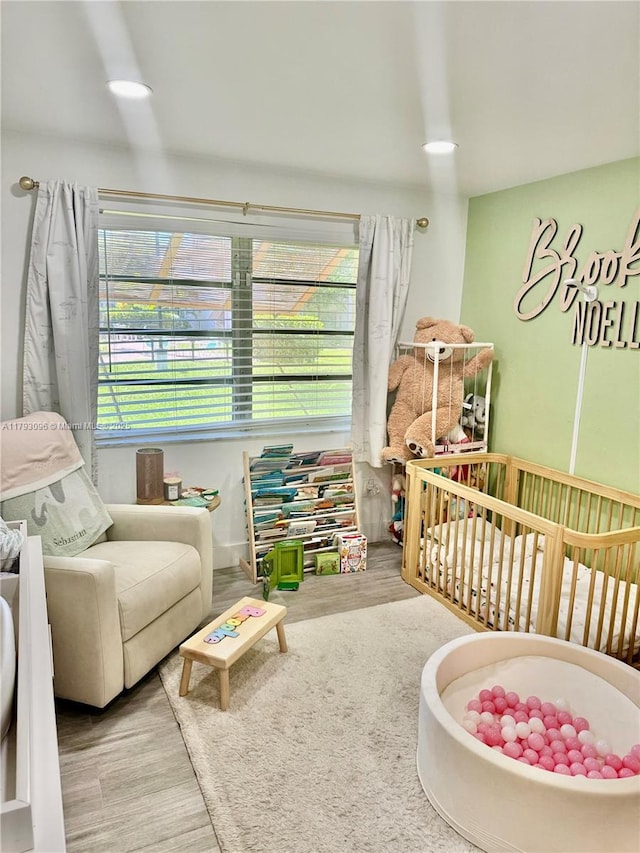 bedroom with a crib and wood finished floors