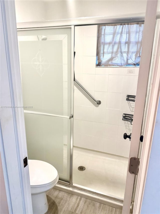 bathroom with wood finished floors, a stall shower, and toilet
