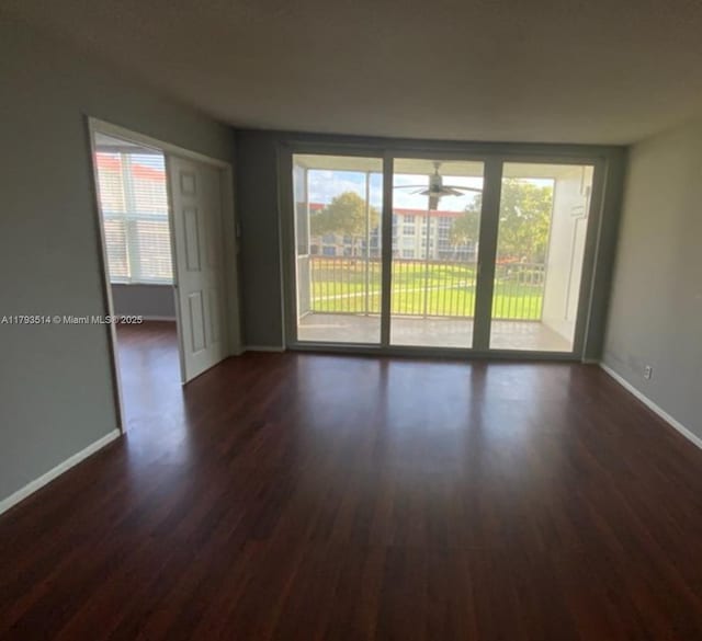 empty room with a ceiling fan, baseboards, plenty of natural light, and dark wood-type flooring