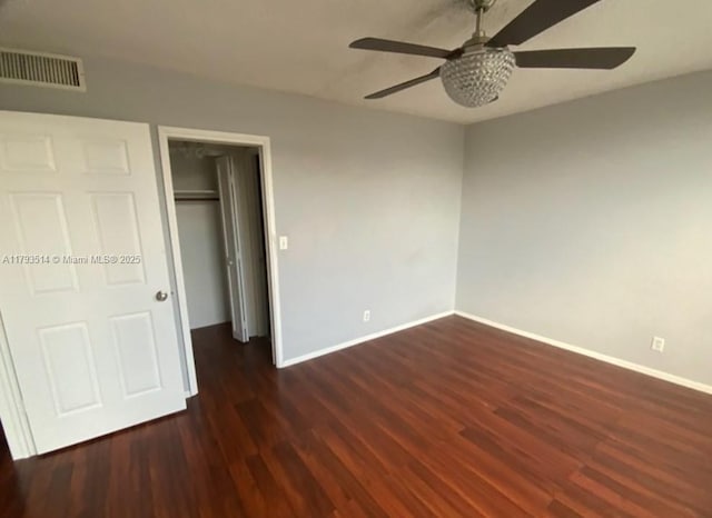 unfurnished bedroom featuring visible vents, a closet, wood finished floors, baseboards, and ceiling fan