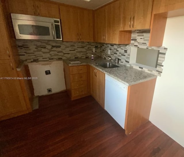 kitchen with a sink, tasteful backsplash, stainless steel microwave, and dark wood finished floors