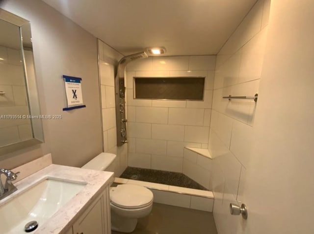 full bathroom with vanity, a tile shower, and toilet