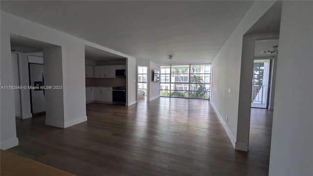 unfurnished living room with baseboards and dark wood finished floors