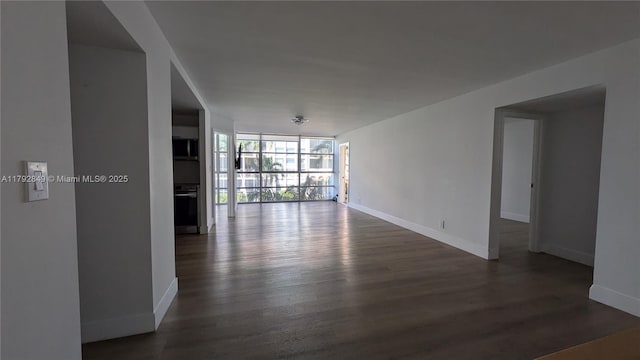 empty room with baseboards, floor to ceiling windows, and dark wood finished floors