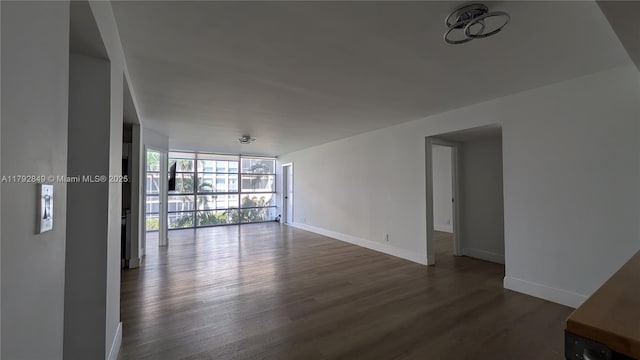 empty room with expansive windows, baseboards, and dark wood-style floors