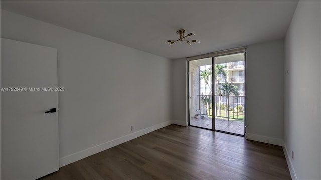 unfurnished room with expansive windows, baseboards, and wood finished floors