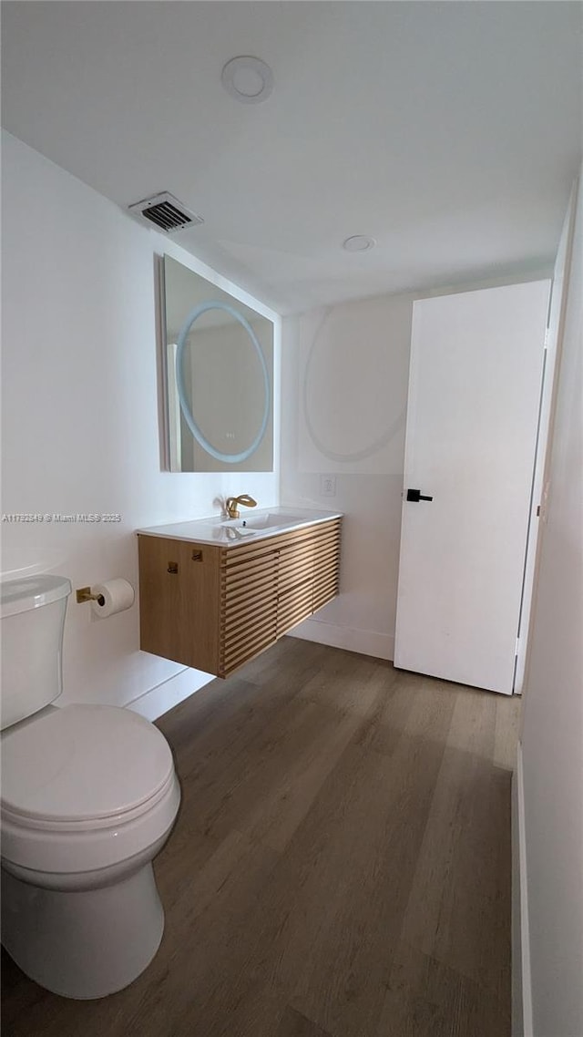 bathroom with vanity, toilet, wood finished floors, and visible vents