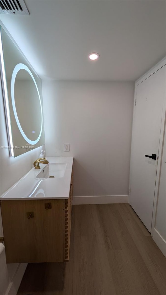 bathroom with vanity, recessed lighting, baseboards, and wood finished floors