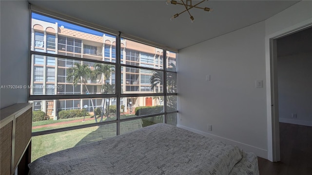 bedroom featuring baseboards, a chandelier, a wall of windows, and wood finished floors