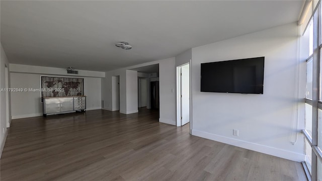 unfurnished living room with baseboards, wood finished floors, and visible vents
