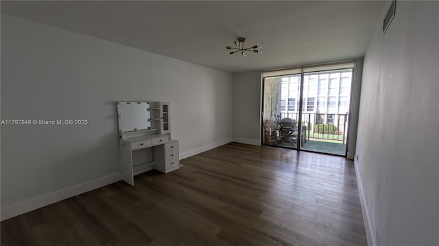 unfurnished room featuring a notable chandelier, baseboards, floor to ceiling windows, dark wood-type flooring, and visible vents