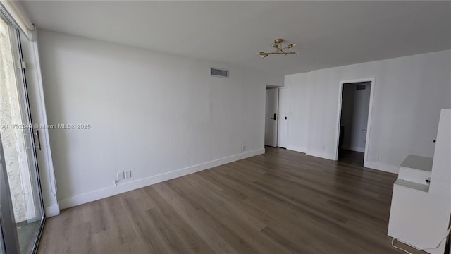 empty room with baseboards, wood finished floors, and visible vents