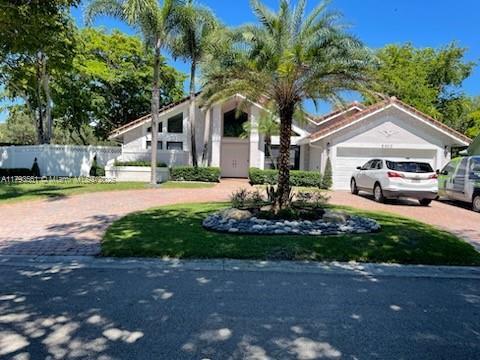 mid-century home with a garage, decorative driveway, and fence