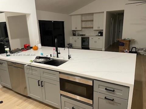 kitchen featuring wine cooler, a sink, vaulted ceiling, gray cabinetry, and stainless steel appliances