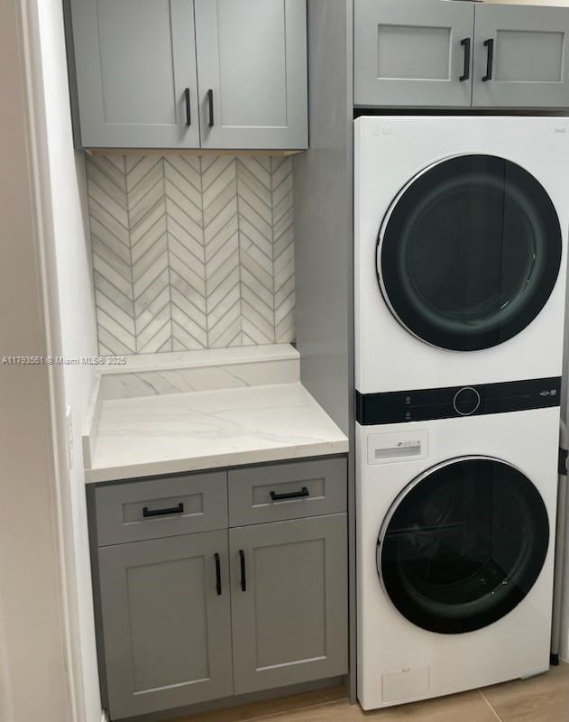 laundry area with cabinet space and stacked washer and clothes dryer