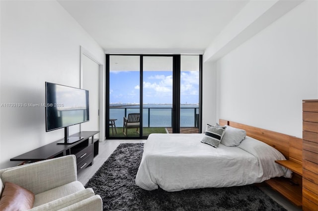 bedroom featuring access to outside, expansive windows, and wood finished floors