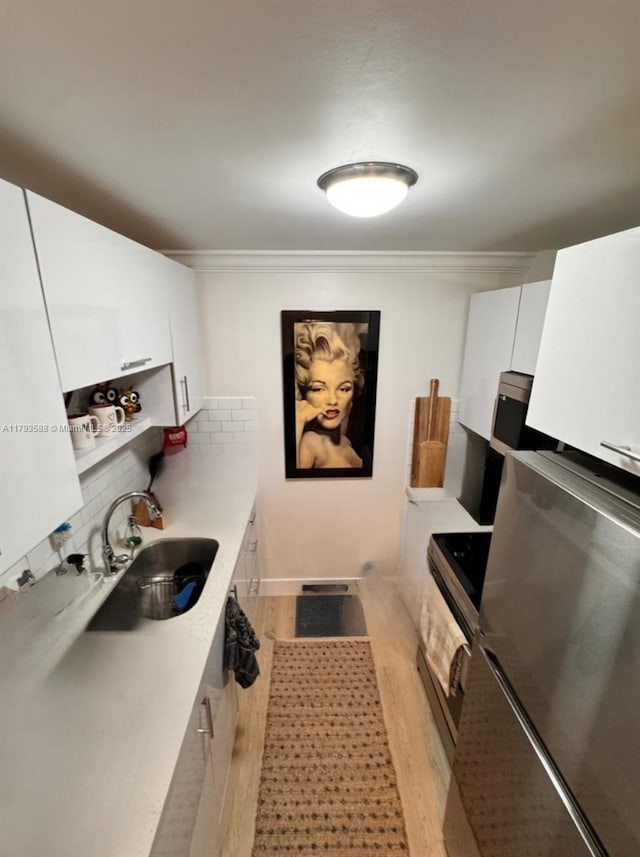 900 Atlantic Shores Blvd Unit 116, Hallandale Beach, FL 33009 - kitchen with a sink, light wood-style floors, white cabinetry, tasteful backsplash, and light countertops