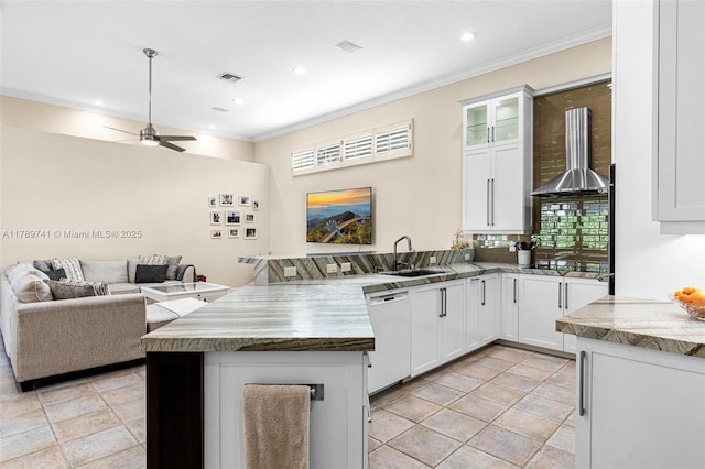 kitchen with wall chimney range hood, visible vents, dishwasher, a sink, and a peninsula