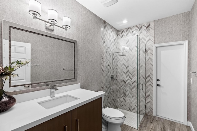 bathroom featuring toilet, a shower stall, wood finished floors, and vanity