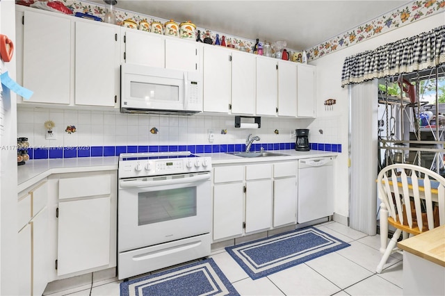 kitchen featuring white appliances, light countertops, white cabinetry, tasteful backsplash, and a sink