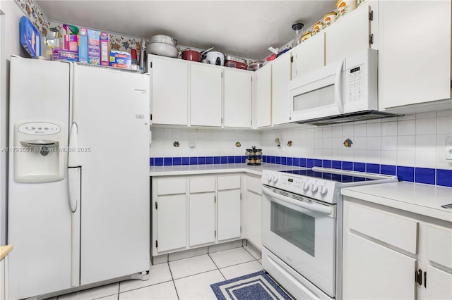 kitchen featuring light countertops, light tile patterned flooring, white appliances, and tasteful backsplash