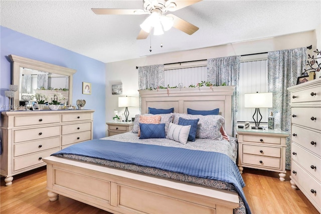 bedroom featuring a textured ceiling, ceiling fan, and light wood-style flooring